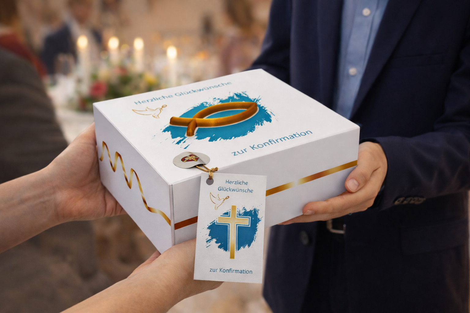 Eine Person in festlicher Kleidung überreicht eine längliche weiße Geschenkbox zur Konfirmation an eine andere Person. Die Box ist mit einem goldenen 3D-Fischsymbol auf türkisfarbenem Hintergrund und einer goldenen Wellenlinie verziert. An der Seite hängt eine Grußkarte mit Kreuzmotiv und dem Text ‚Herzliche Glückwünsche zur Konfirmation‘. Der Hintergrund ist warm und unscharf und erinnert an eine Feier.