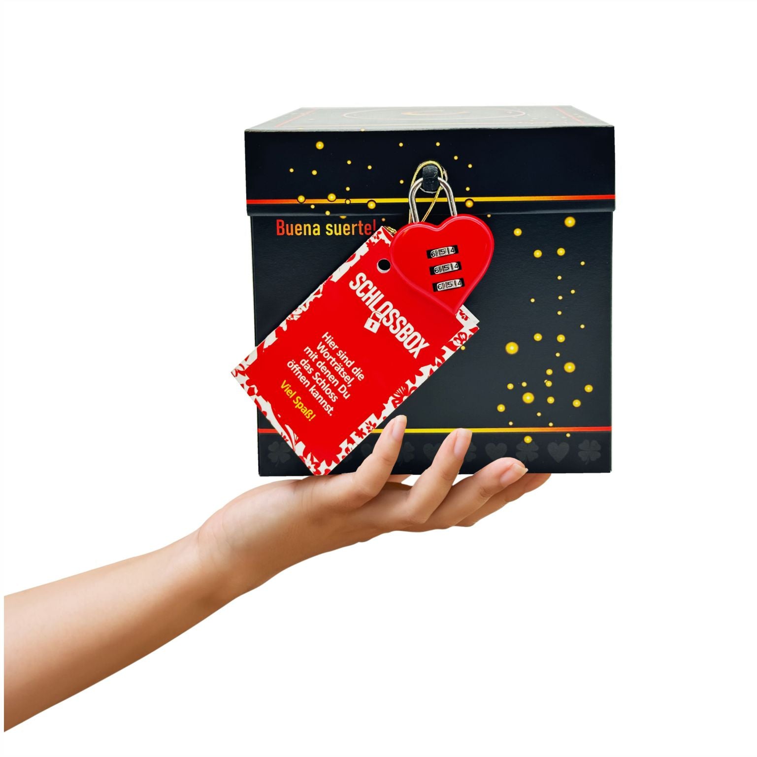 Rätselbox Glück in Schwarz mit rotem Herz-Zahlenschloss und Rätselheft-Anhänger, gehalten in einer Hand vor weißem Hintergrund. Aufschrift vorne an der Box: Buena suerte!