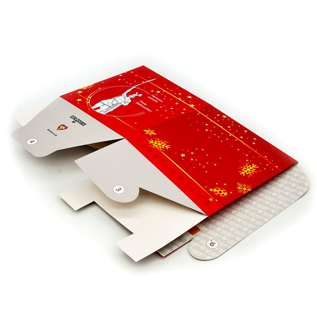 Weihnachtliche Rätselbox Hermannsdenkmal in Rot mit goldenen Stern- und Schneeflockenmotiven, flach liegend für den Versand.