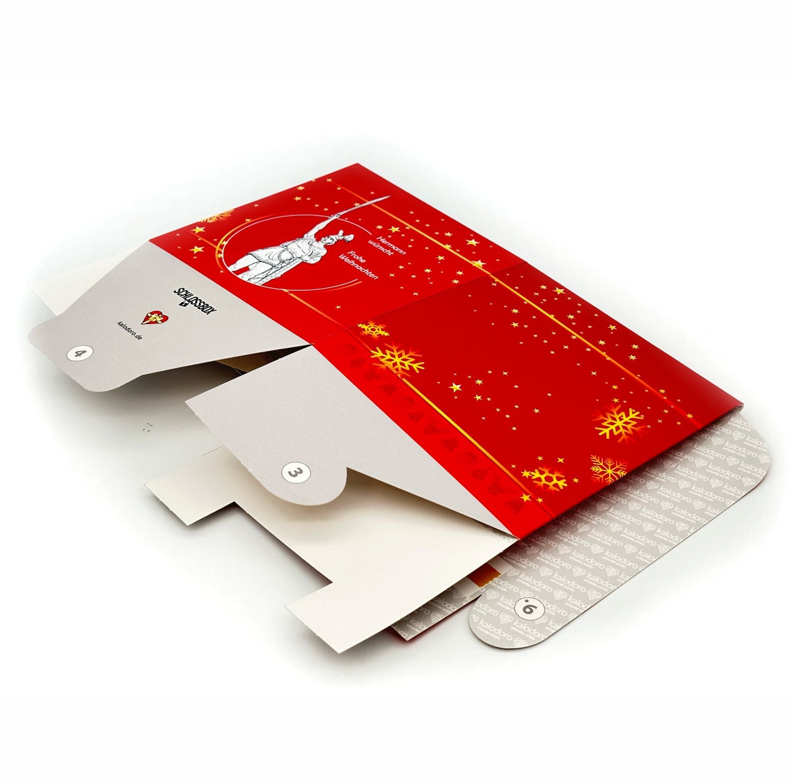 Weihnachtliche Rätselbox Hermannsdenkmal in Rot mit goldenen Stern- und Schneeflockenmotiven, flach liegend für den Versand.
