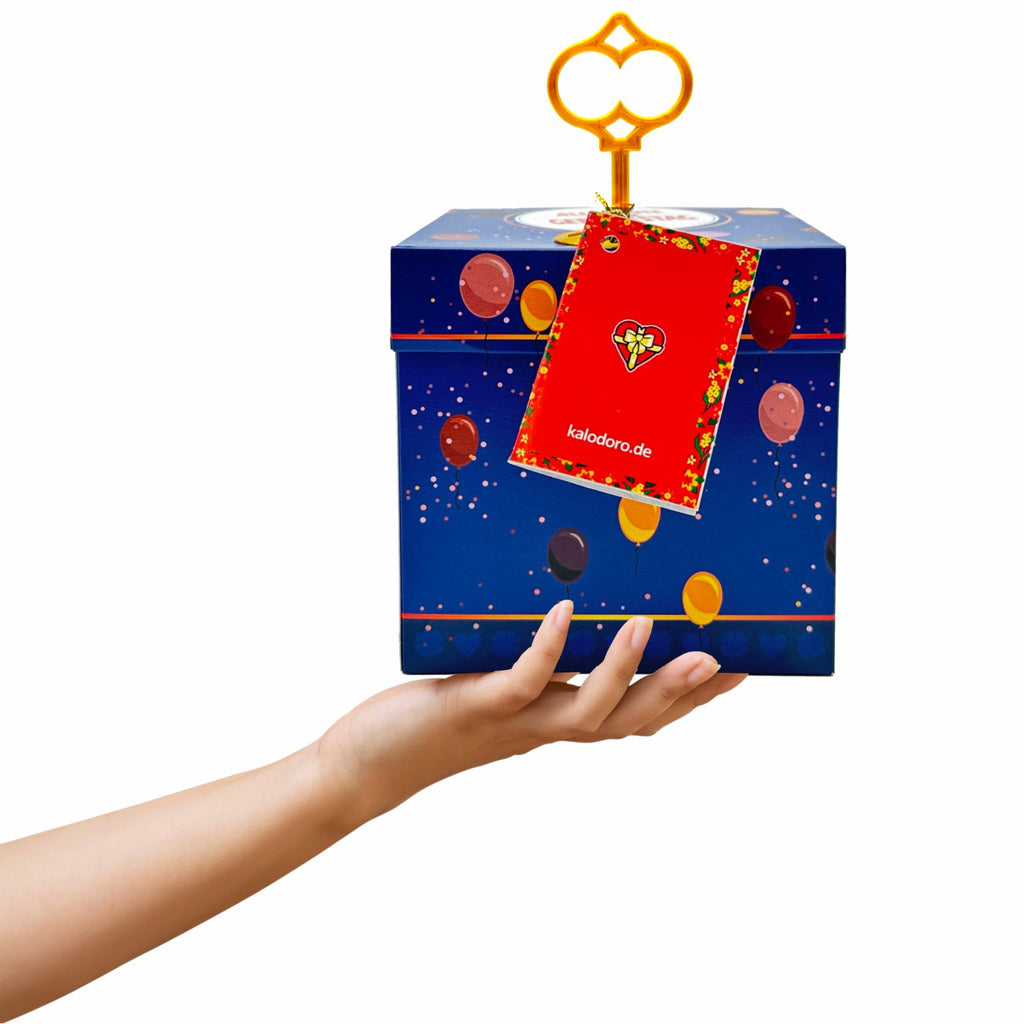 Schlossbox Geburtstag in Blau mit Ballonmotiven, oben eingesteckter goldener Schlüssel und rotes Grußheftchen, in einer Hand gehalten.