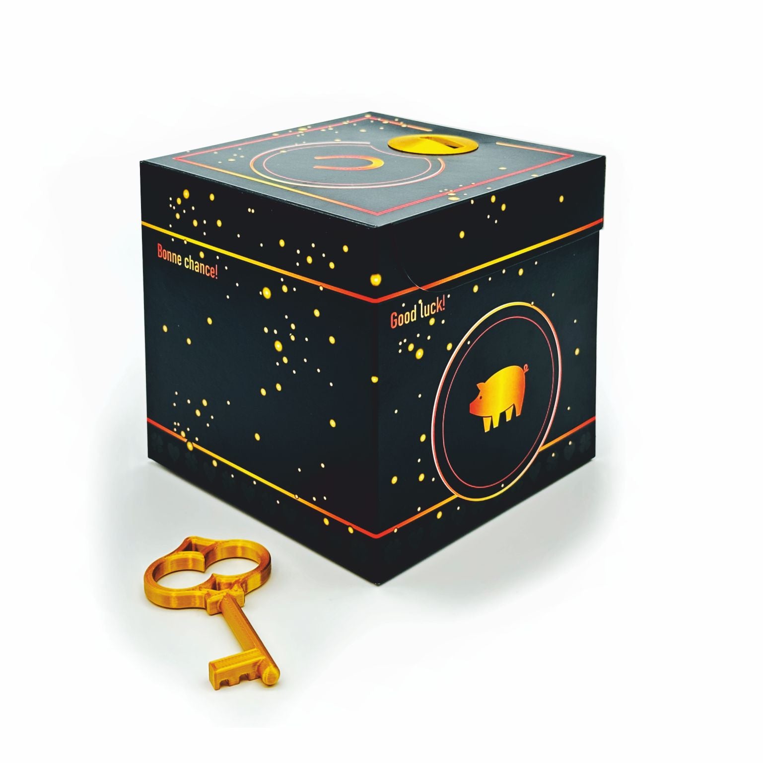 Geschlossene Schlossbox Glück in Schwarz mit goldenen Sprenkeln und Glücksschwein-Motiv, seitlich Schriftzüge ‚Good luck‘ und ‚Bonne chance‘, goldener Schlüssel liegt vor der Box