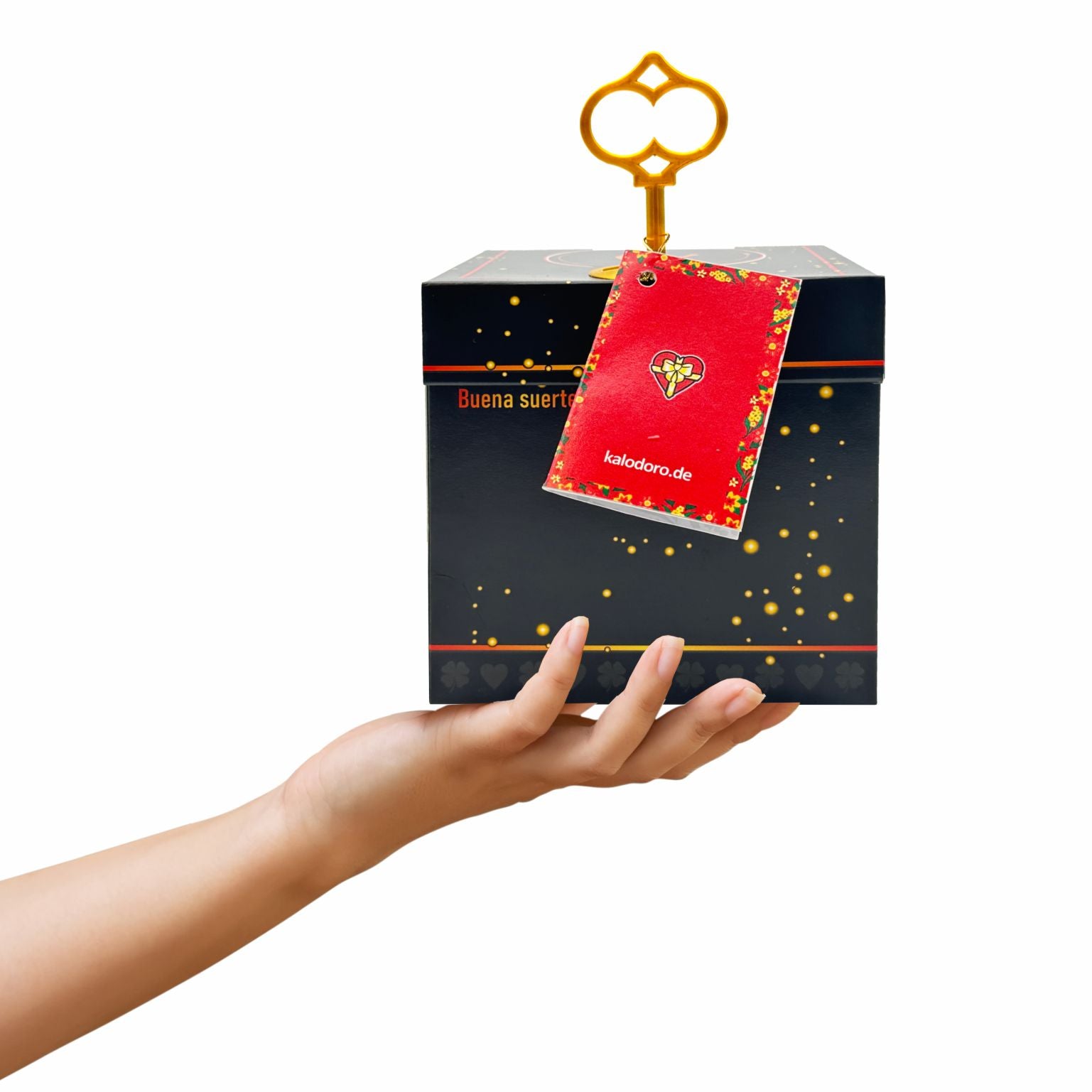 Schwarze Schlossbox Glück mit goldenen Sprenkeln, dekorativer goldener Schlüssel steckt oben in der Box, rotes Grußheftchen befestigt, Präsentation in einer Hand.